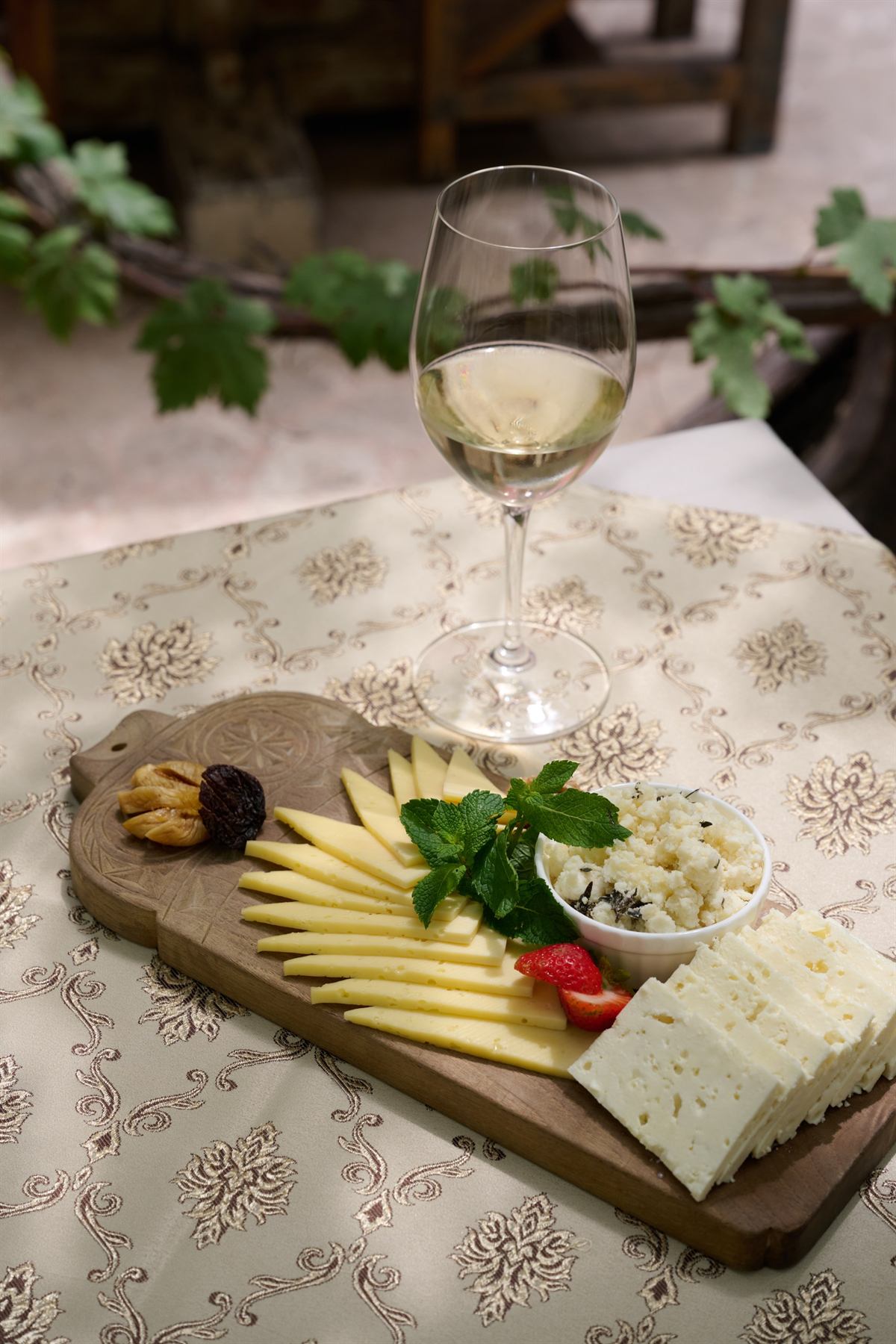 Wooden board with five Armenian cheeses and white wine